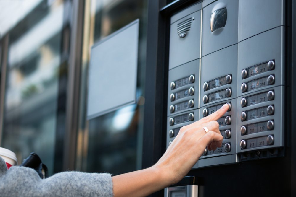 close,up,of,woman,using,intercom,at,residential,building,entrance.